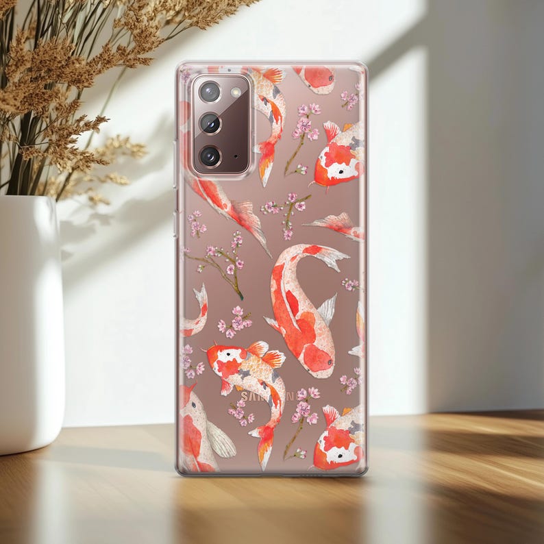 May include: A clear phone case with a design of orange and white koi fish swimming among pink cherry blossoms. The case is designed for a Samsung Galaxy S21 Ultra.
