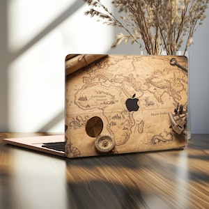 May include: A laptop featuring a skin with an antique map design, displaying geographical labels like Aethiopia Interior and Mare Indicum. The design includes illustrations of a brass compass, a sextant, a key, and sea creatures on a parchment background.