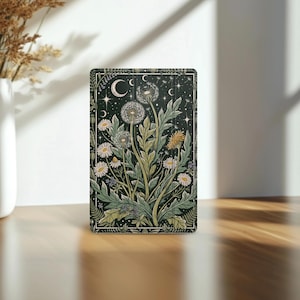May include: A rectangular tablet case featuring a dark background with a botanical illustration of dandelions, daisies, and green foliage. The design includes celestial elements like crescent moons and stars, framed by a decorative border.