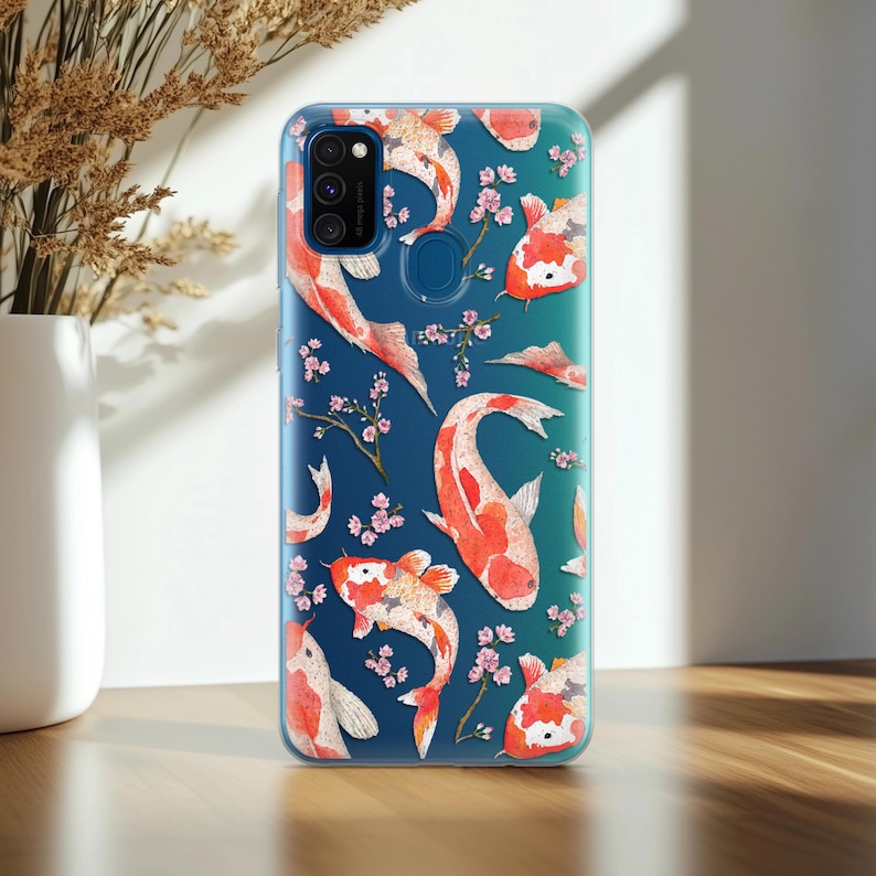 May include: A clear phone case with a blue background and a pattern of orange and white koi fish and pink cherry blossoms.