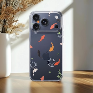 Può includere: Una cover trasparente per smartphone con un motivo stampato di pesci koi arancioni, bianchi e neri che nuotano tra piccole ninfee verdi e disegni circolari di increspature dell'acqua. La cover presenta un'apertura per la tripla fotocamera.