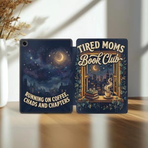 Pode incluir: Uma capa de tablet azul marinho com um design de céu noturno e o texto "Running on Coffee, Chads and Chapters." A capa aberta revela uma cena de janela com o texto "Tired Moms Book Club", uma paisagem urbana, livros e uma xícara de café.