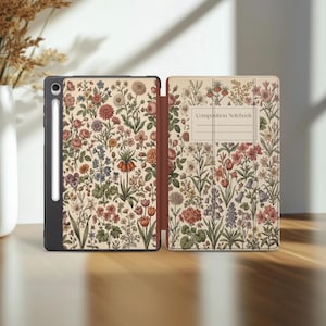 Könnte beinhalten: Eine Tablethülle mit cremefarbenem Hintergrund und einem dichten, bunten botanischen Druck aus verschiedenen Blumen und Blättern. Das Frontcover enthält ein rechteckiges Etikett mit dem Text Composition Notebook und einen Stifthalter.
