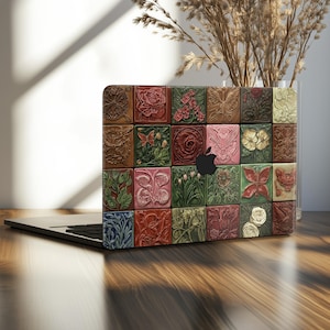May include: A laptop with a decorative cover featuring a mosaic of embossed floral and butterfly designs in various colours, including red, green, and brown. The Apple logo is visible. The laptop is on a wooden surface.
