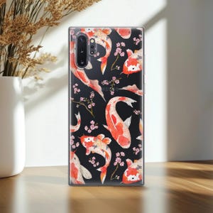 May include: A clear phone case with a black background and a repeating pattern of red and white koi fish and pink cherry blossoms.