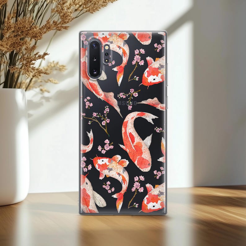 May include: A clear phone case with a black background and a repeating pattern of red and white koi fish and pink cherry blossoms.