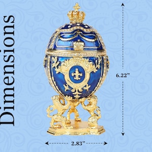 May include: A decorative blue and gold egg-shaped trinket box with a crown on top. The box is 6.22 inches tall and 2.83 inches wide. The egg is supported by three golden lion figures. The box is embellished with gold filigree and rhinestones.