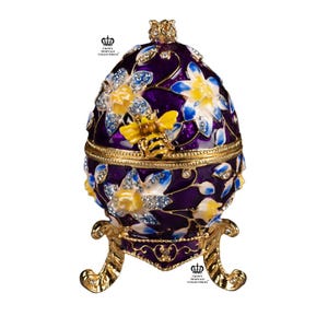 Faberge type egg with bee and flower purple with floral pattern with Swarovski crystals opens to hold jewelry or trinkets. It is 3.75” tall