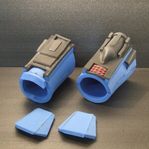 Op de afbeelding: Twee blauwe en zwarte foam polsmanchetten met een klein rood knopje paneel op een manchet. Twee extra blauwe foam stukken zijn ook inbegrepen.