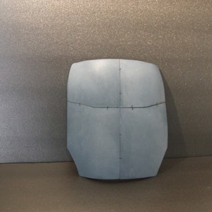 May include: A blue, rectangular, flat, rigid object with a textured surface and black lines across it.