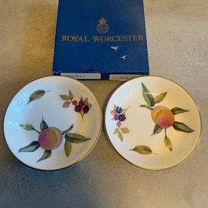 May include: Two white porcelain bowls with gold rims and a peach and blackberry design. The bowls are from Royal Worcester and are part of the Arden pattern.