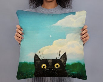 May include: A black cat with yellow eyes peeks out from behind a green field. The cat is looking up at a blue sky with white clouds and a crescent moon.