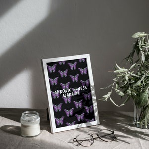 May include: White framed print with a black background and a repeating pattern of purple butterflies. The text "CHRONIC ILLNESS WARRIOR" is printed in white in the center of the print.