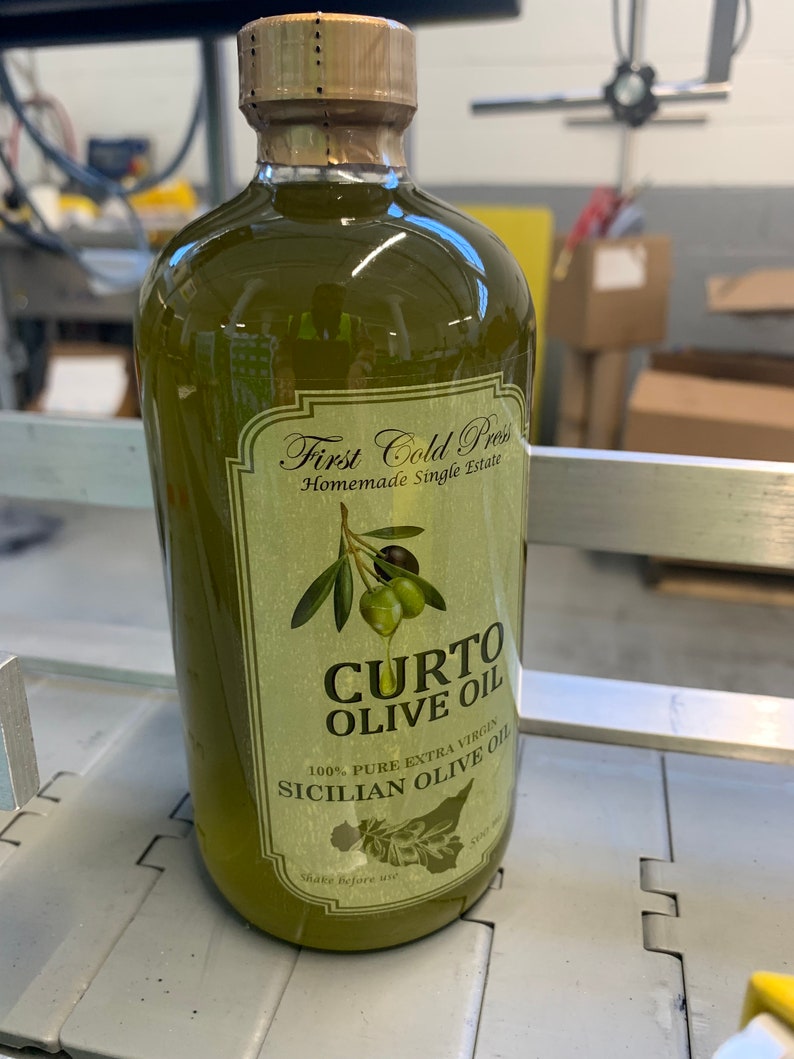 Puede incluir: Una botella de vidrio de aceite de oliva verde con una etiqueta que dice "First Cold Press Homemade Single Estate CURTO OLIVE OIL 100% PURE EXTRA VIRGIN SICILIAN OLIVE OIL".