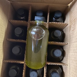Puede incluir: Una caja de cart&oacute;n llena de doce botellas de vidrio con tapas negras. Las botellas est&aacute;n dispuestas en forma de cuadr&iacute;cula. Las botellas est&aacute;n llenas de un l&iacute;quido transparente.