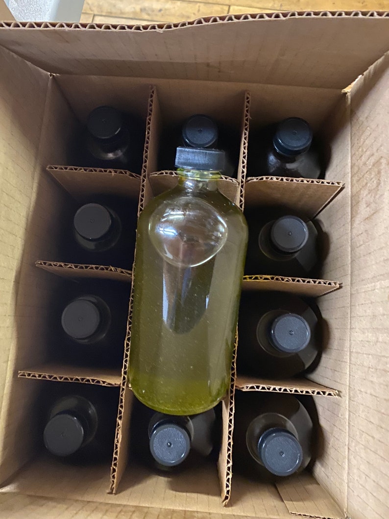 Puede incluir: Una caja de cart&oacute;n llena de doce botellas de vidrio con tapas negras. Las botellas est&aacute;n dispuestas en forma de cuadr&iacute;cula. Las botellas est&aacute;n llenas de un l&iacute;quido transparente.