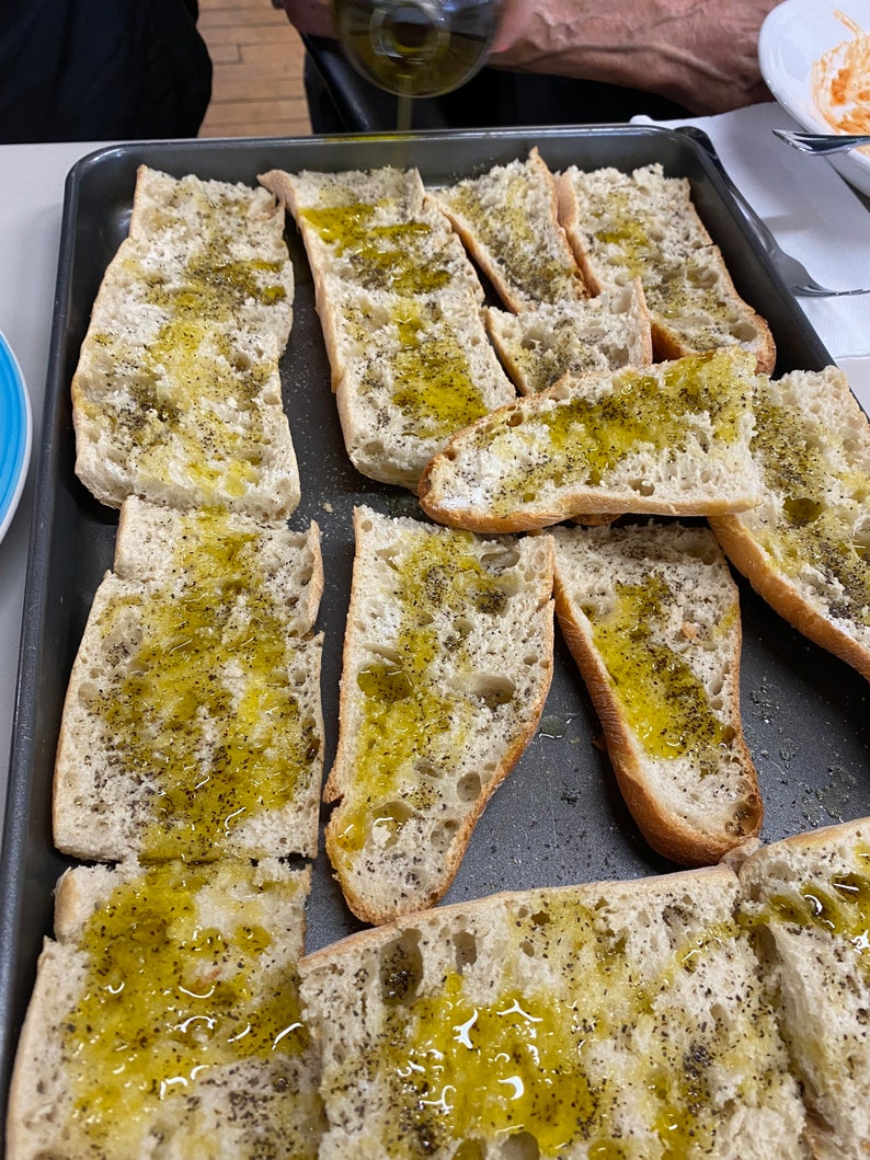 May include: A baking sheet filled with slices of bread brushed with olive oil and sprinkled with black pepper.