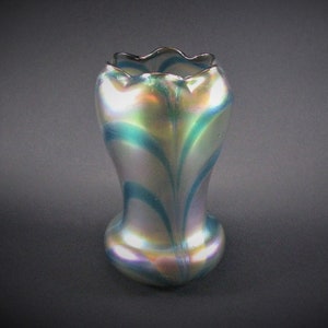 Puede incluir: Un jarrón de vidrio iridiscente con un borde festoneado y patrones de remolino azul y verde.