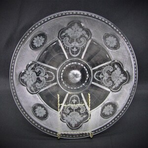 May include: A clear glass plate with an etched design of flowers and leaves. The plate has a beaded edge and a central design of a starburst.