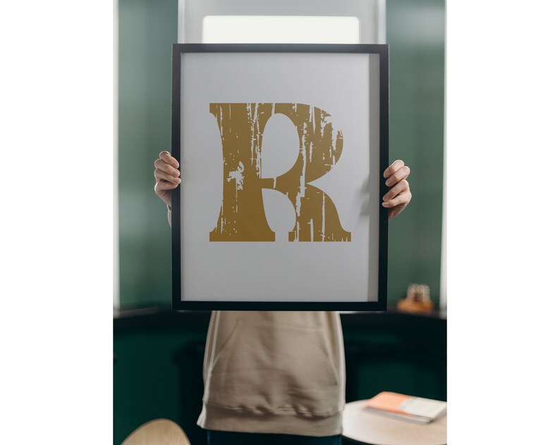 May include: A framed print of the letter "R" in a distressed gold font on a white background.