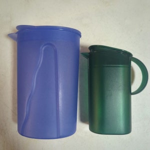 Könnte beinhalten: Zwei Plastikkannen, eine blaue und eine grüne. Die blaue Kanne ist größer und hat einen Griff auf der linken Seite. Die grüne Kanne ist kleiner und hat einen Griff auf der rechten Seite.