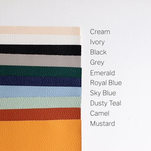 May include: A collection of 11 leather swatches in various colours, including cream, ivory, black, grey, emerald, royal blue, sky blue, dusty teal, camel, and mustard.