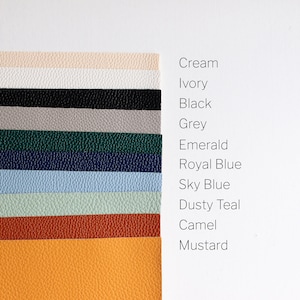 May include: A collection of 11 leather swatches in various colors, including cream, ivory, black, gray, emerald, royal blue, sky blue, dusty teal, camel, and mustard.