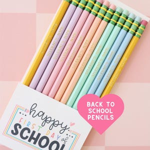 May include: A box of pastel-colored pencils with the text "STUDENT'S NAME" printed on each. The box has a "happy FIRST DAY of SCHOOL" design and a pink heart that says "BACK TO SCHOOL PENCILS".