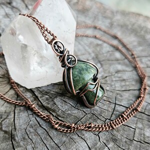 May include: A copper chain necklace with a green moss agate pendant wrapped in copper and silver wire.
