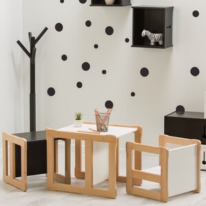 May include: A black and white playroom with a table and chairs, a coat rack, and storage cubes. The walls are decorated with black polka dots.