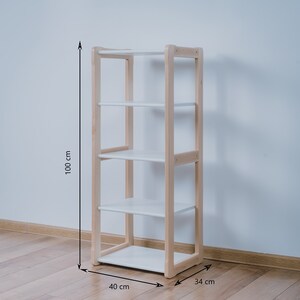 May include: A white shelf unit with four shelves and a natural wood frame. The shelf unit is 40 inches wide, 34 inches deep, and 100 inches tall.