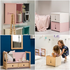May include: A set of three wooden storage boxes painted in pink, white and blue. The boxes are stacked on top of each other and feature a cut-out design on the front. The boxes are displayed on a white shelf.