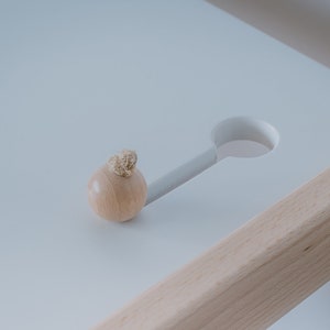 K&ouml;nnte beinhalten: Ein Holzgriff mit einem Seildetail sitzt auf einer wei&szlig;en Oberfl&auml;che mit einem Ausschnitt. Die Oberfl&auml;che ist Teil eines Holztisches.