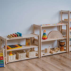 May include: Wooden shelves filled with colorful educational toys for children, including a rainbow stacking toy, a xylophone, a counting abacus, and a wooden rainbow arch.