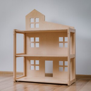 Puede incluir: Una casa de mu&ntilde;ecas de madera natural, con un techo en forma de casa y varias ventanas cuadradas. La casa de mu&ntilde;ecas tiene dos estantes y una puerta en el nivel inferior. El juguete est&aacute; dise&ntilde;ado para ni&ntilde;os.