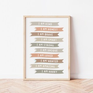 K&ouml;nnte beinhalten: Ein gerahmter Druck mit wei&szlig;em Hintergrund und einer Reihe von bunten Bannern mit positiven Affirmationen. Der Text auf den Bannern lautet: "Ich bin freundlich", "Ich bin ehrlich", "Ich bin mutig", "Ich bin klug", "Ich bin stark", "Ich bin einzigartig", "Ich bin geliebt", "Ich bin gewollt", "Ich bin gro&szlig;artig", und "Ich bin Harry".