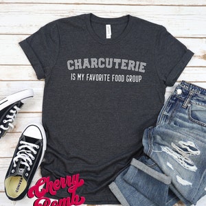 Peut inclure: Un t-shirt gris fonc&eacute; avec du texte blanc qui dit "Charcuterie est mon groupe alimentaire pr&eacute;f&eacute;r&eacute;".