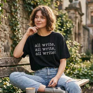 May include: A black short-sleeved t-shirt featuring the white text "all write, all write, all write!" printed on the front. The shirt is paired with light blue denim jeans and gray boots, creating a casual look for everyday wear.