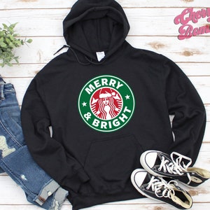 May include: Black hoodie with a green and red graphic of a Starbucks logo with the text "Merry & Bright" on a white background.