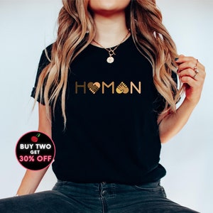 May include: Black t-shirt with the word "HUMAN" spelled out with a heart, handshake, and fist bump graphic in the middle of the word.