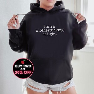 May include: Black hoodie with the text "I am a motherfucking delight." in white. A red and white cherry graphic with the text "Buy Two Get 30% Off" is in the lower left corner.