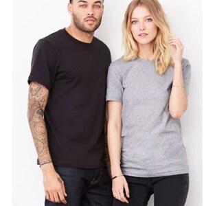 Peut inclure: Deux personnes portant des t-shirts, l'un noir et l'autre gris, se tenant l'un &agrave; c&ocirc;t&eacute; de l'autre. La personne &agrave; gauche porte un jean bleu et la personne &agrave; droite porte un pantalon noir.