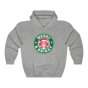 May include: A gray hooded sweatshirt with a green and white logo that says "Merry & Bright" with a stylized image of a woman wearing a Santa hat.