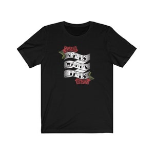 May include: Black t-shirt featuring a white banner with the text "Cats and Tats" and red roses on either side.
