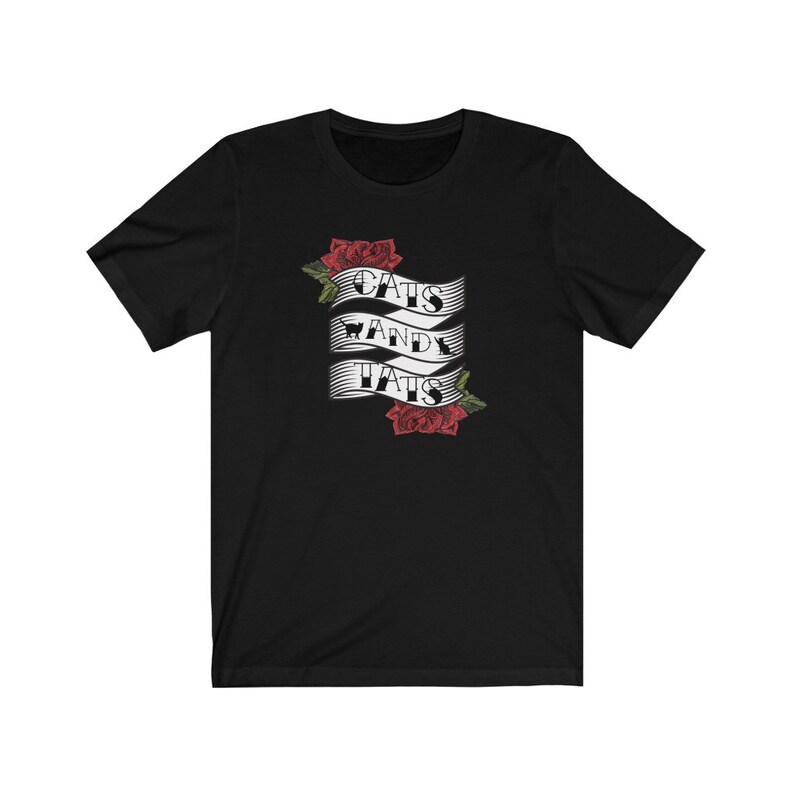 May include: Black t-shirt featuring a white banner with the text "Cats and Tats" and red roses on either side.