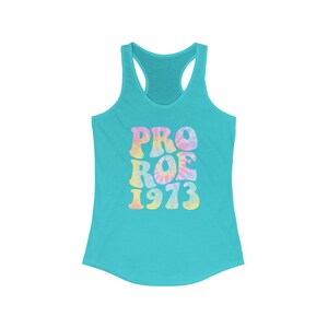 May include: A turquoise racerback tank top with the words "PRO ROE 1973" in a tie-dye design. The text is in pastel colors, including pink, yellow, and blue. The tank top has a scoop neck and a racerback design.
