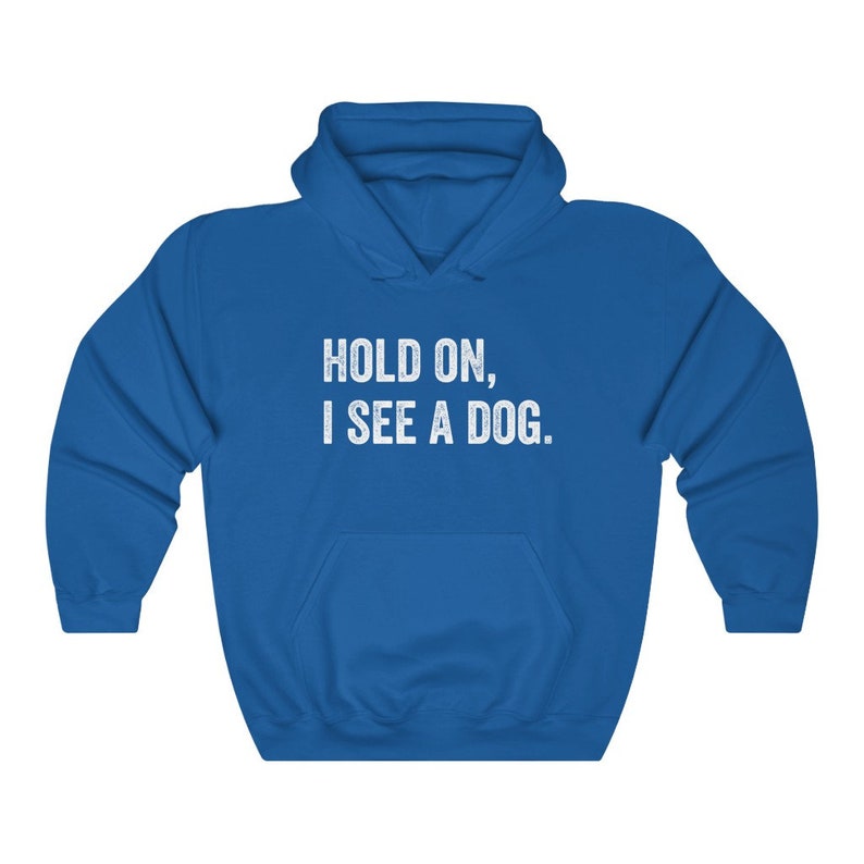 Pode incluir: Uma camisa de frio com capuz azul royal com o texto "HOLD ON, I SEE A DOG." impresso em branco.