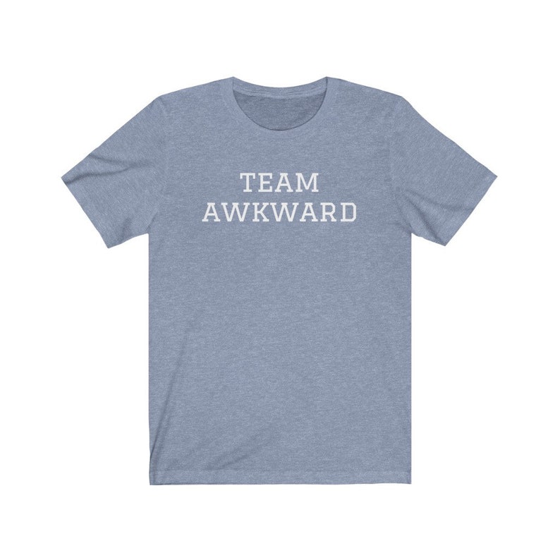 May include: A light blue t-shirt with the text "TEAM AWKWARD" printed in white on the front.