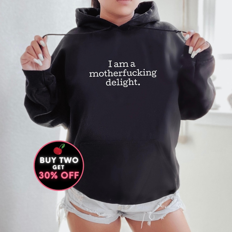 May include: Black hoodie with the text "I am a motherfucking delight." in white. A red and white cherry graphic with the text "Buy Two Get 30% Off" is in the lower left corner.