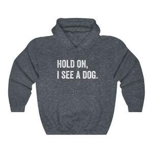 Pode incluir: Um moletom cinza escuro com o texto "HOLD ON, I SEE A DOG." impresso em branco.